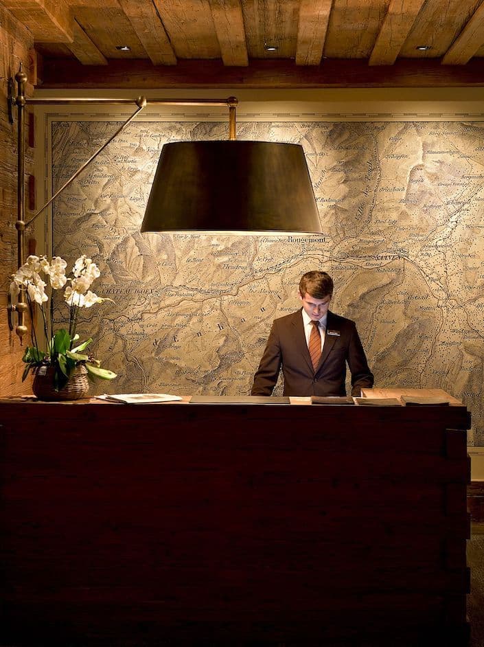 A hotel reception desk backed by a large map wall, standing in for how one channel-manager connection distributes a listing across booking platforms